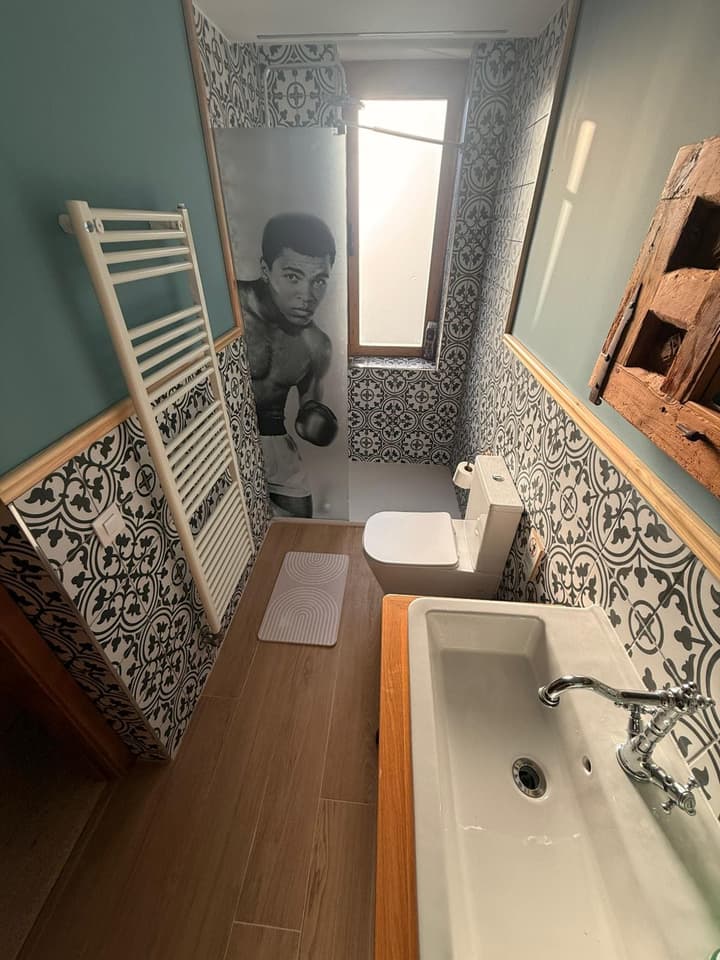 Baño reformado con azulejo hidráulico en blanco y negro, toallero radiador y mampara decorada