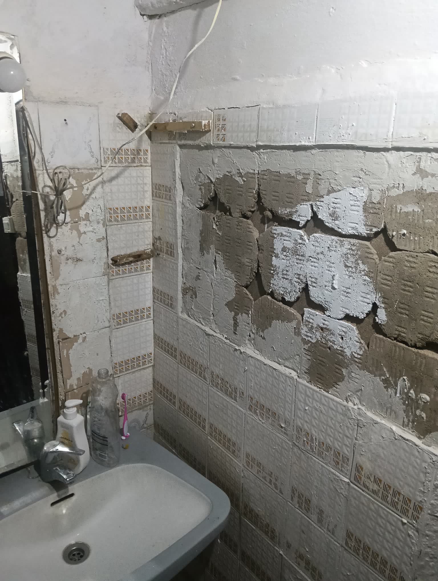Pared picada con el alicatado retirado y los cables de la instalación eléctrica a la vista