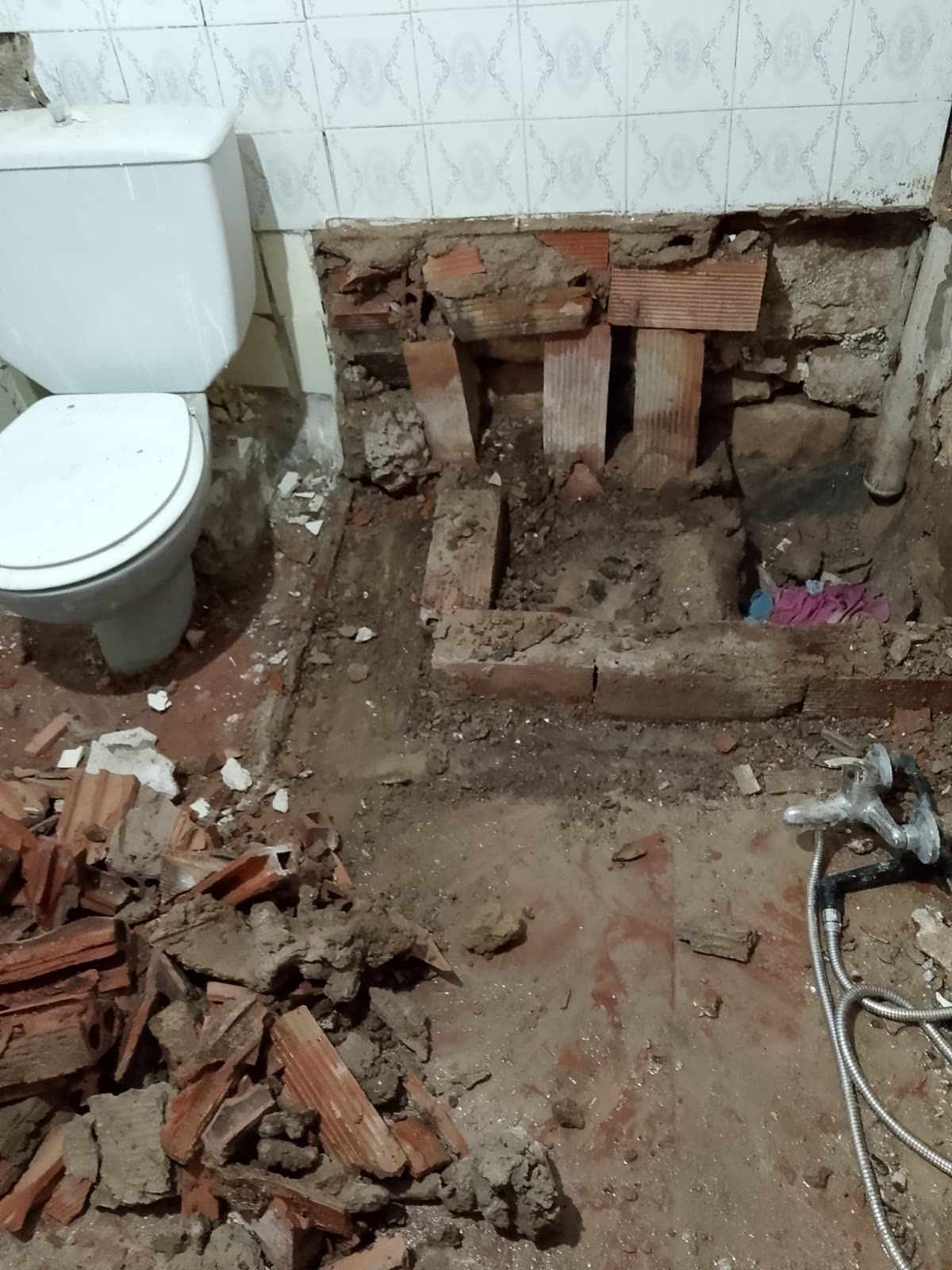 Hueco de la bañera demolido, con rasilla cerámica vista y escombro