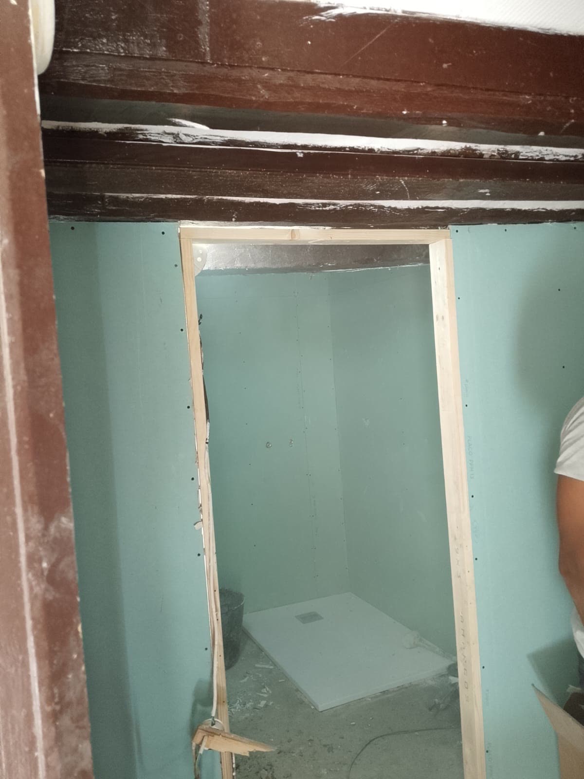 Vano de puerta enmarcado en madera maciza bajo una viga original de tejado