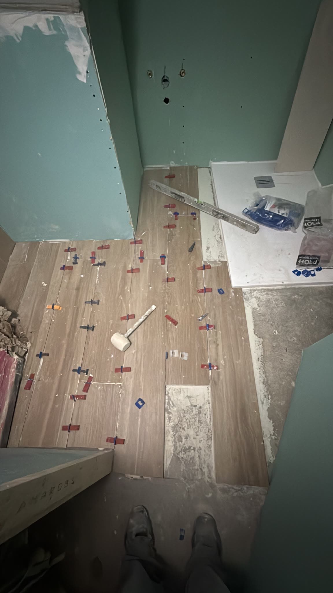 Suelo de un baño en obra con piezas de porcelánico colocadas y las crucetas de nivelación aún puestas