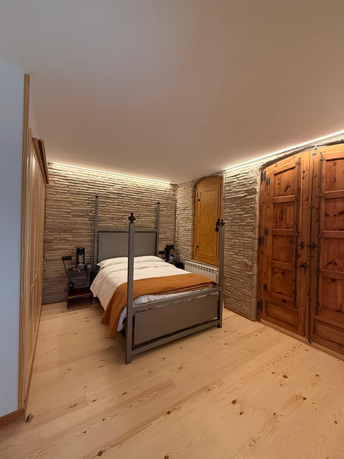 Dormitorio con pared de piedra vista y cama de forja en una vivienda de Arnedo